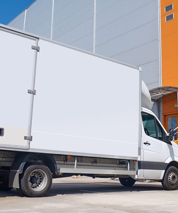 Car, warehouse. White cargo covered vehicle standing outdoors in parking lot near warehouse on fine day